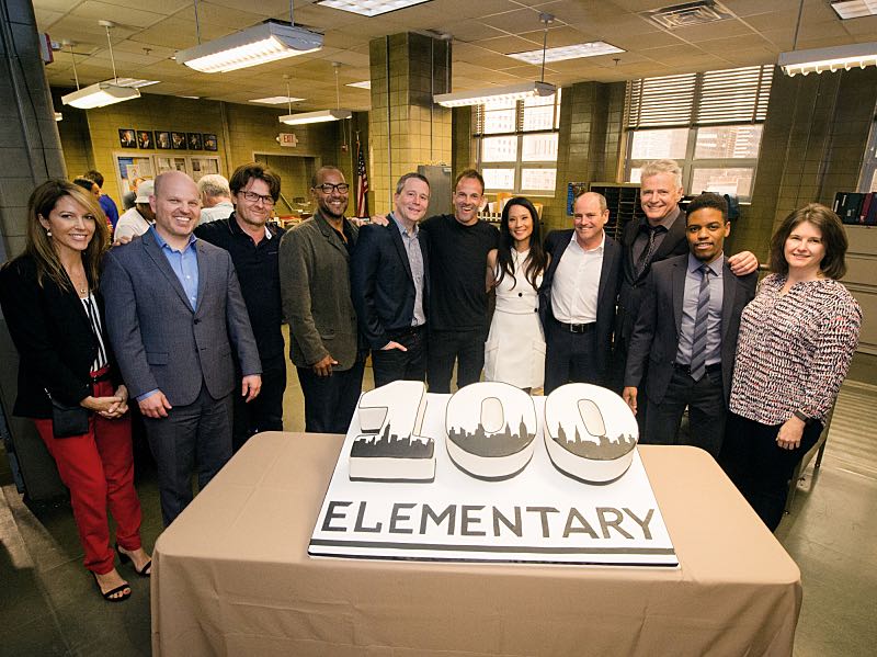 The cast of ELEMENTARY celebrates their milestone 100th episode with a cake-cutting ceremony Pictured (L-R) Bridget Wiley Executive Vice President, Current Programs, CBS Entertainment and CBS Television Studios, Glenn Geller President, CBS Entertainment, Executive Producers John Polson, Carl Beverly, Rob Doherty, Jonny Lee Miller Lucy Liu, David Stapf President, and CBS Television Studios Aidan Quinn, Jon Michael Hill and Kim Metcalf Photo: JEFF NEIRA /CBS é2016 CBS Broadcasting Inc. All Rights Reserved.